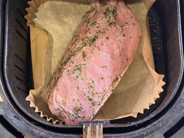 The garlic herb pork loin laid in a parchment-lined air fryer basket