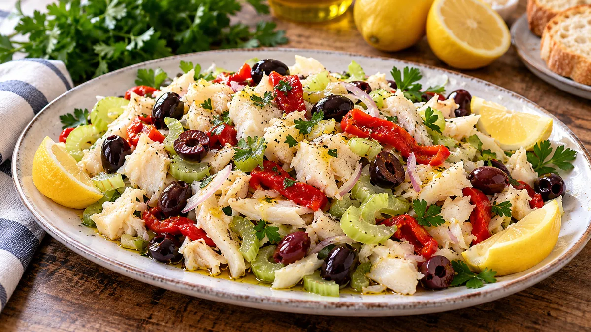 Platter of baccala salad with flaked salt cod, celery, black olives, red peppers and lemon