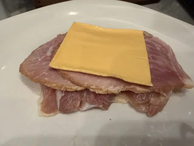 Ham and a slice of cheese laid on the flattened chicken
