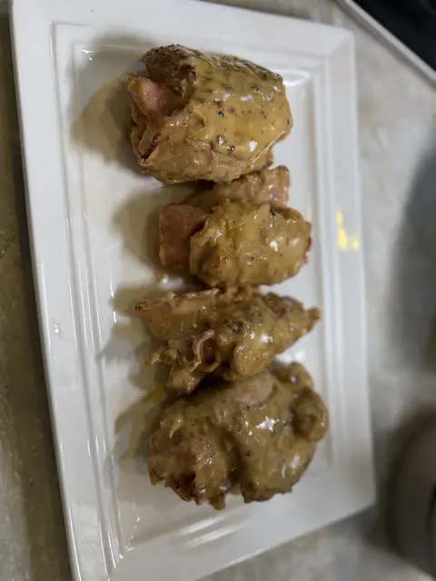 Chicken cordon bleu on a platter, covered in the cream sauce
