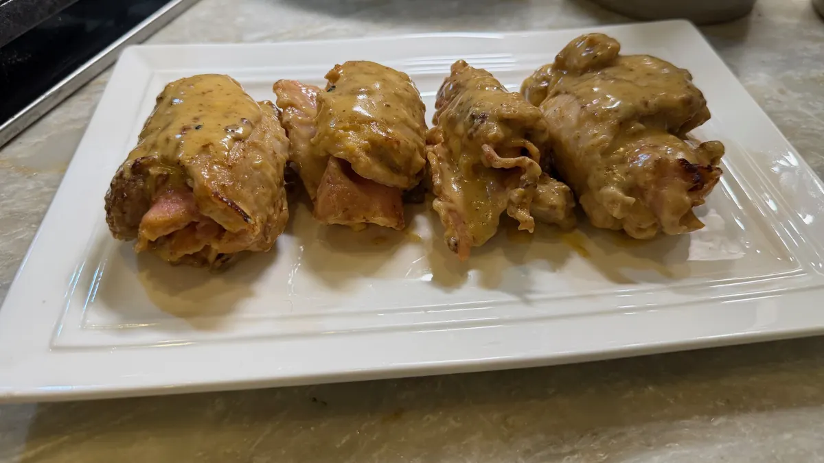 Chicken cordon bleu bundles in cream sauce on a white platter, photographed in Sofia's kitchen