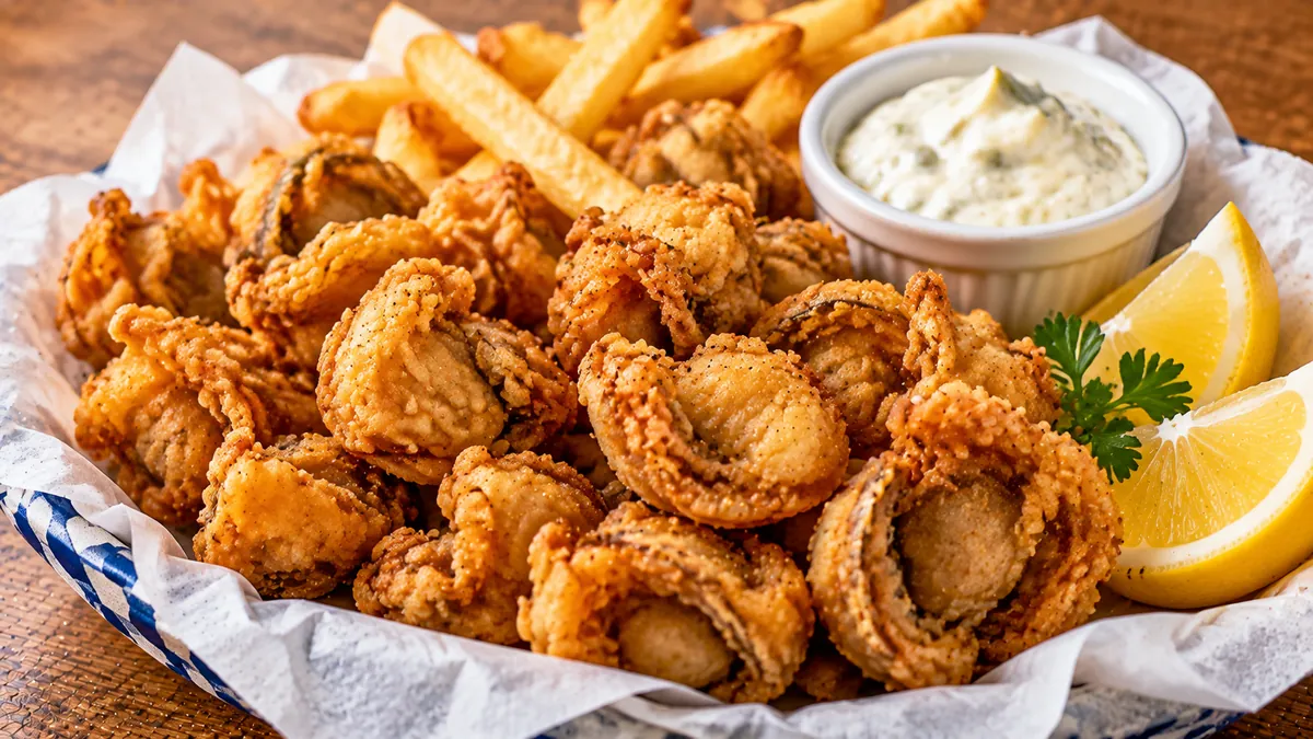 Basket of crispy fried whole-belly clams with tartar sauce, lemon and fries